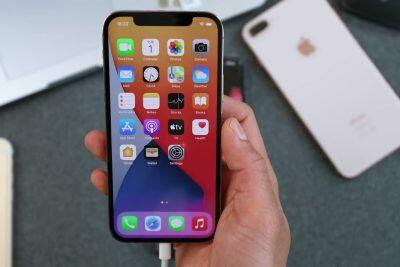 Mano sosteniendo un iPhone dorado mostrando aplicaciones.